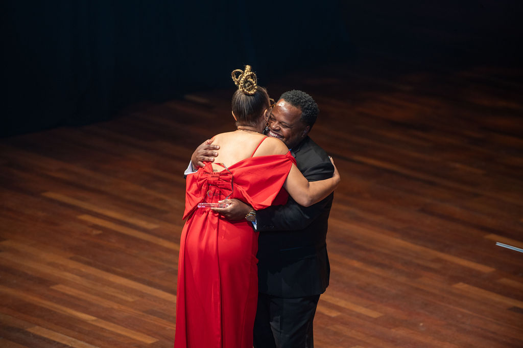 Presenter and winner hugging on stage at the Schermerhorn
