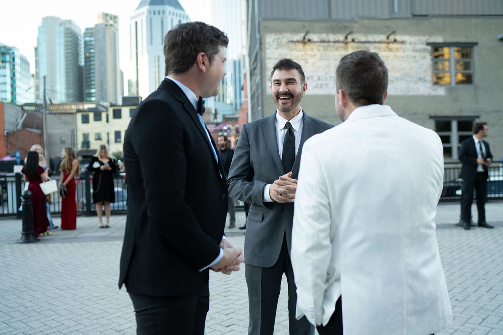 Three men laughing outside with Nashville skyline behind them