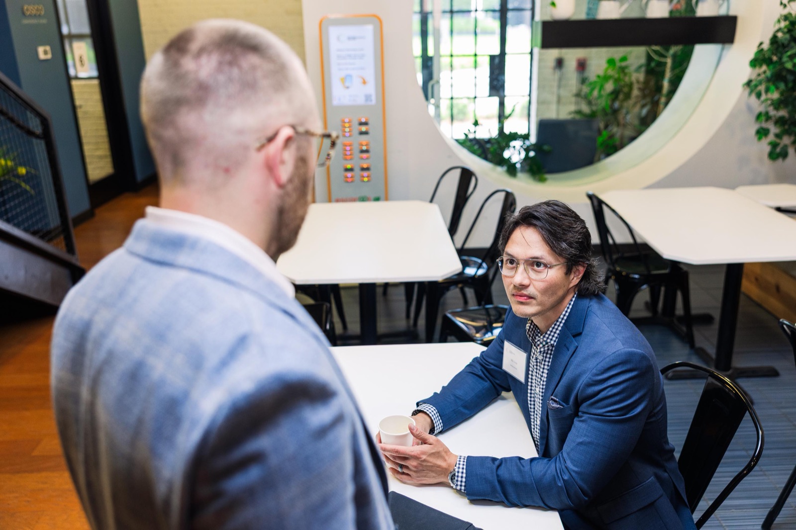 An advisor and a founder seated across a white table in a one-on-one meeting at the EC