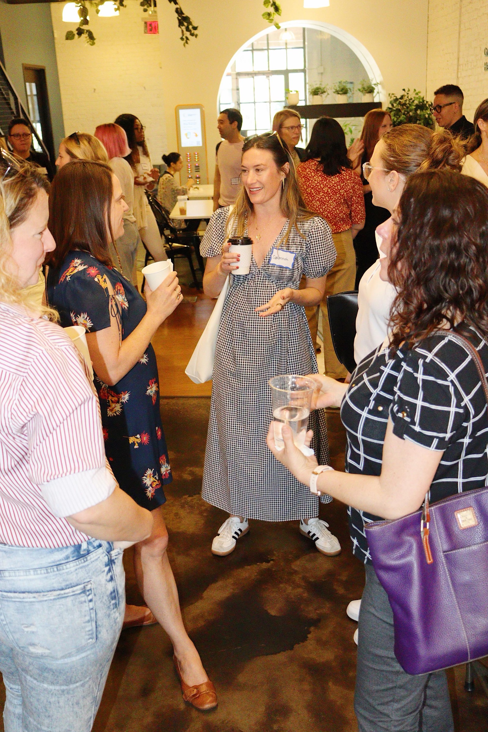 A group of members standing in conversation with coffee cups in the EC lobby
