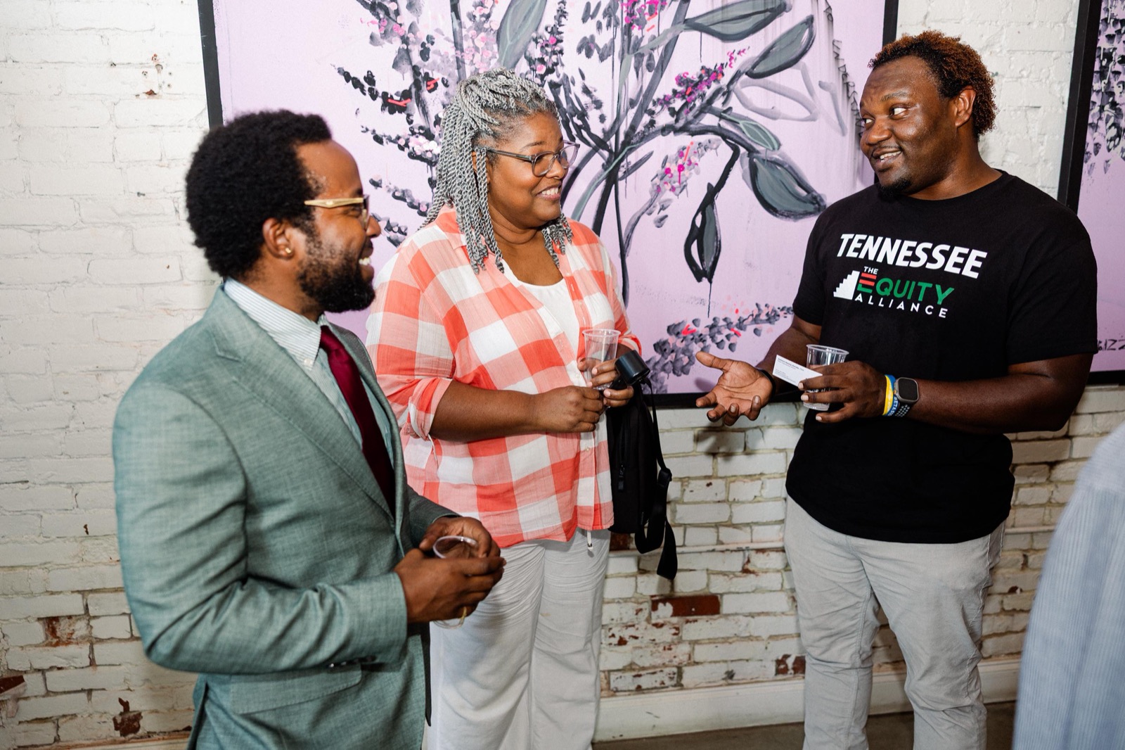 Three founders exchanging a business card mid-conversation