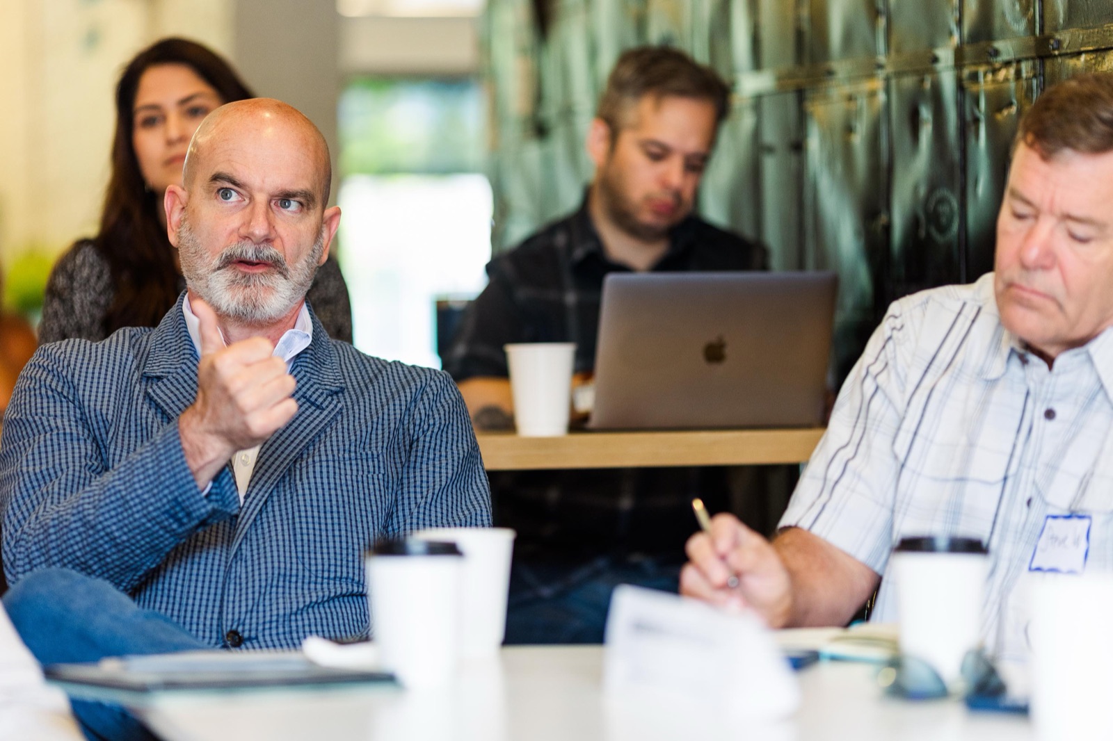 An entrepreneur-in-residence listening across a table from InFlight founders working on laptops