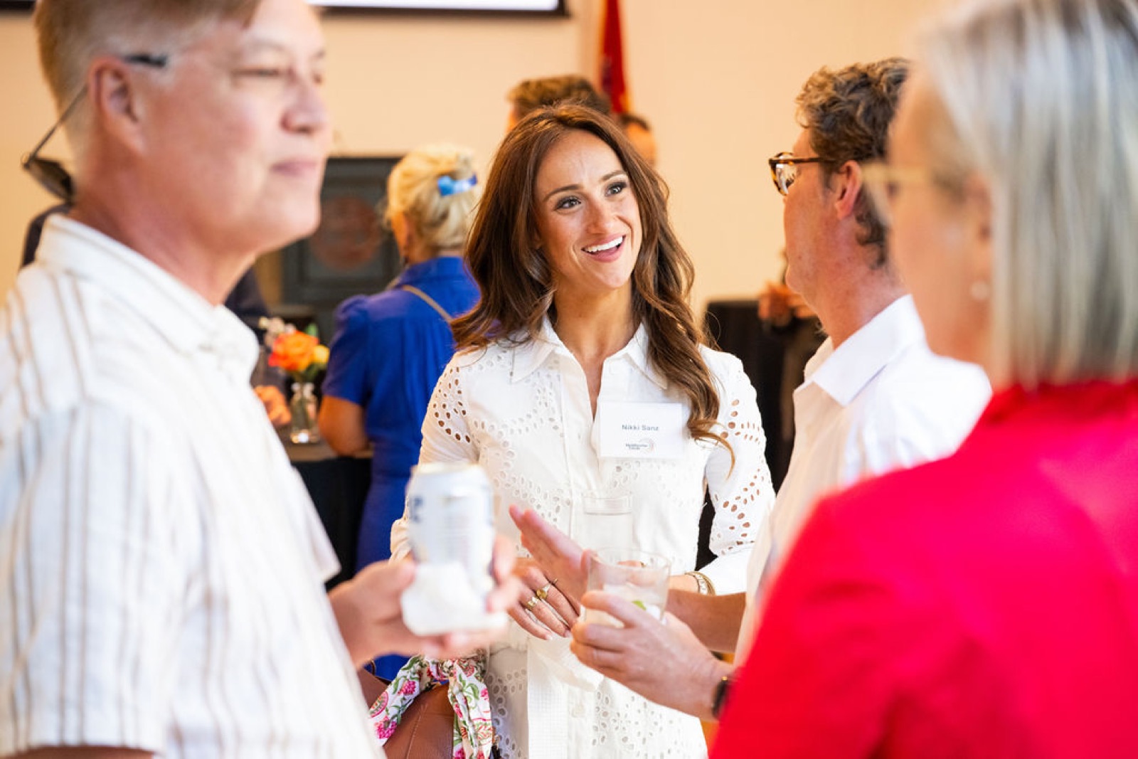 Guests with drinks in conversation at the reception, one smiling mid-sentence