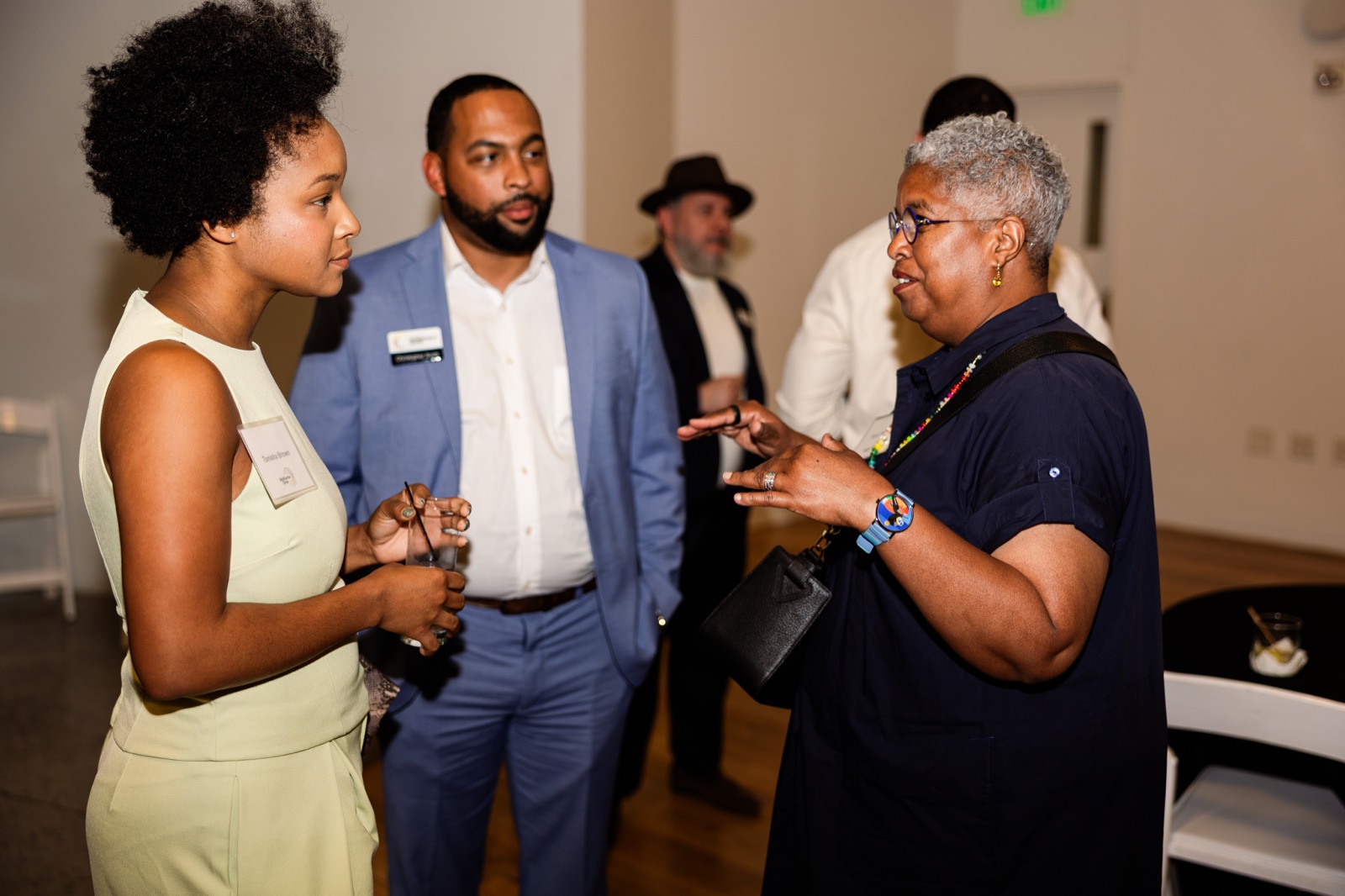 Four guests in animated conversation near the door of the hall