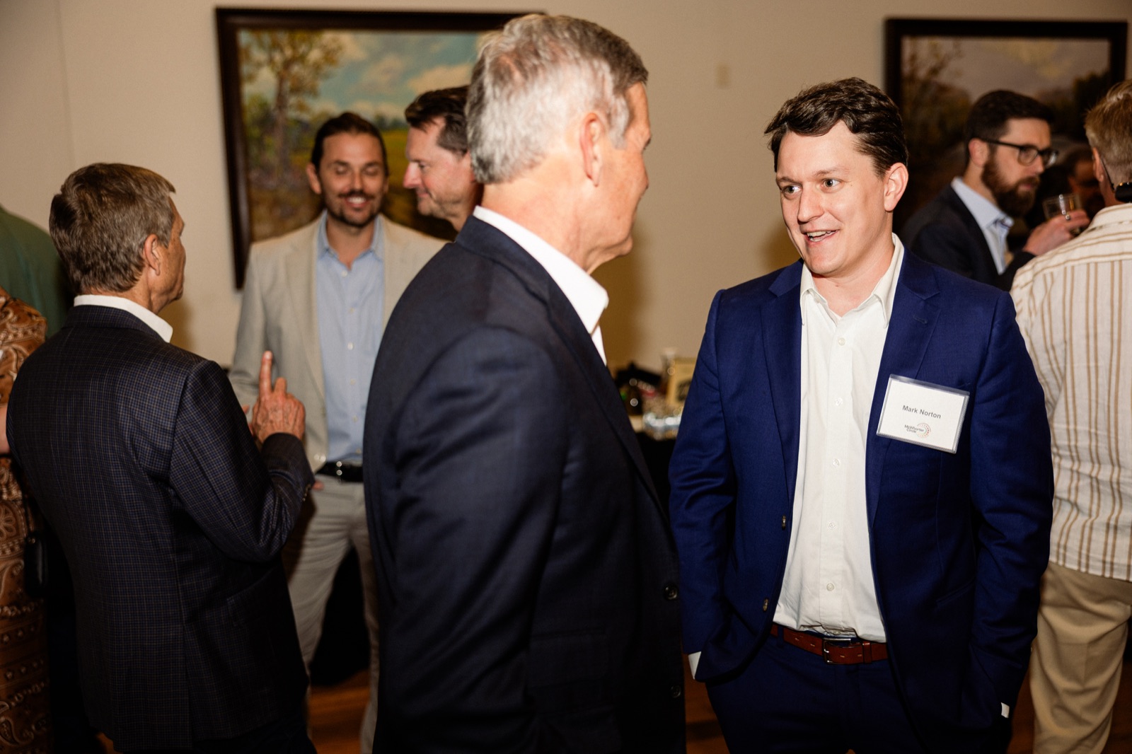 Guests in conversation at the reception, one gesturing as he speaks