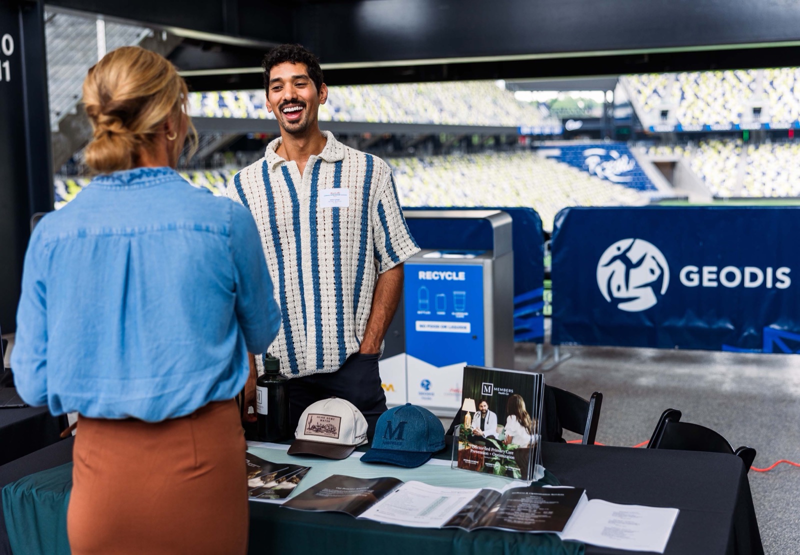 A founder smiling at his expo booth while talking with an attendee