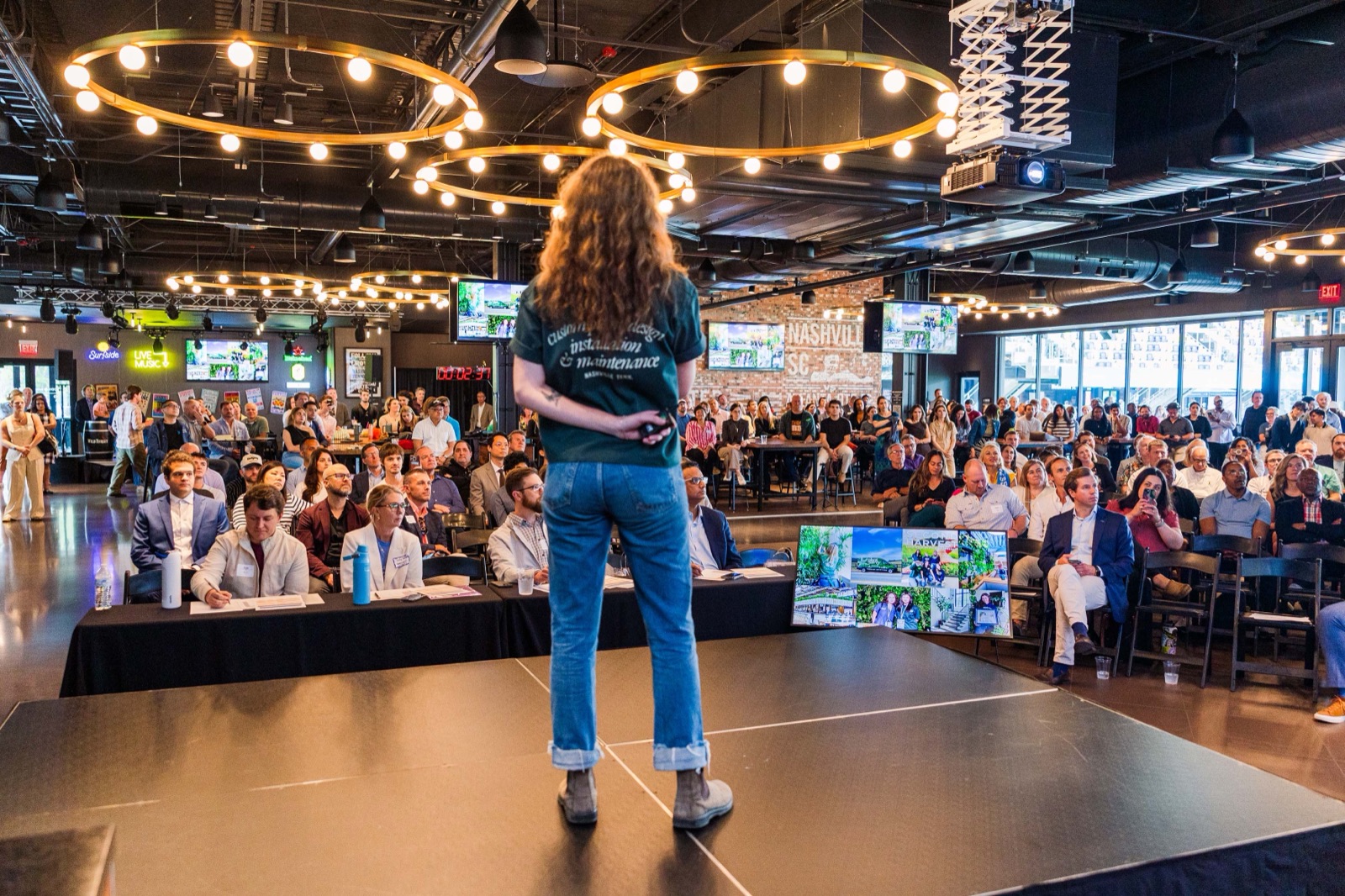 A founder pitching on stage to a full room at Nashville Entrepreneur Day, seen from behind