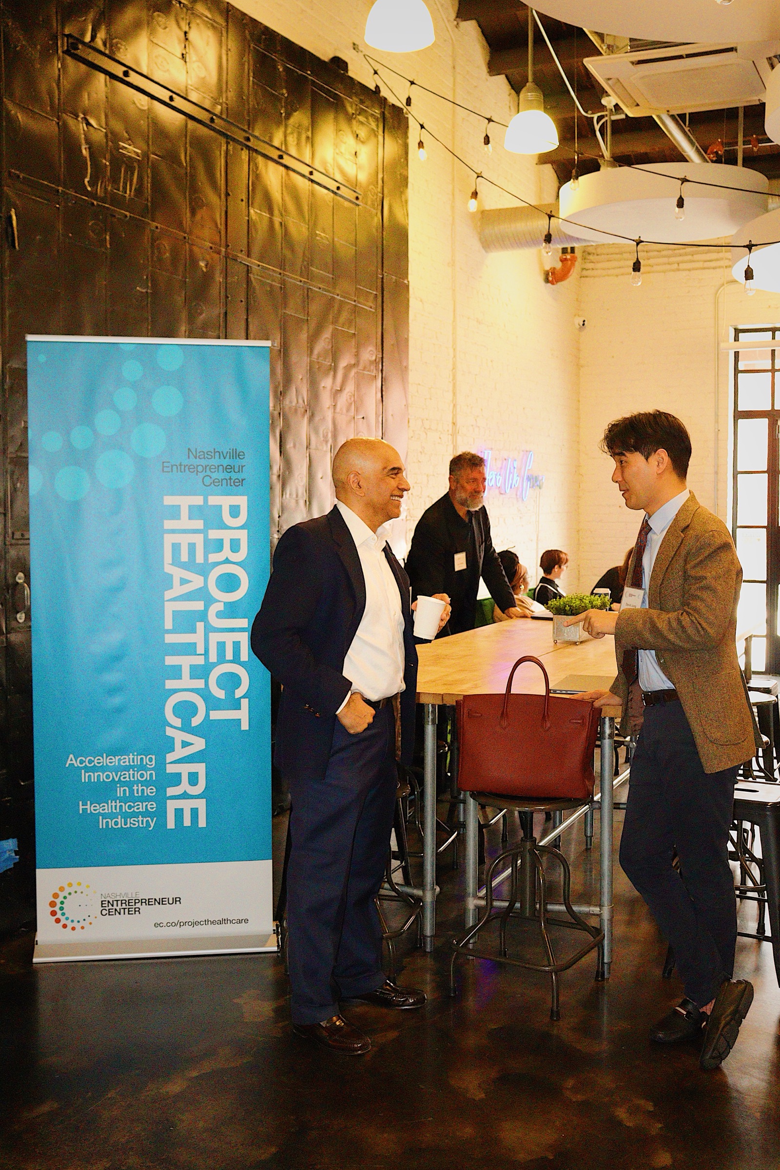 Project Healthcare founders in conversation beside the program banner between sessions