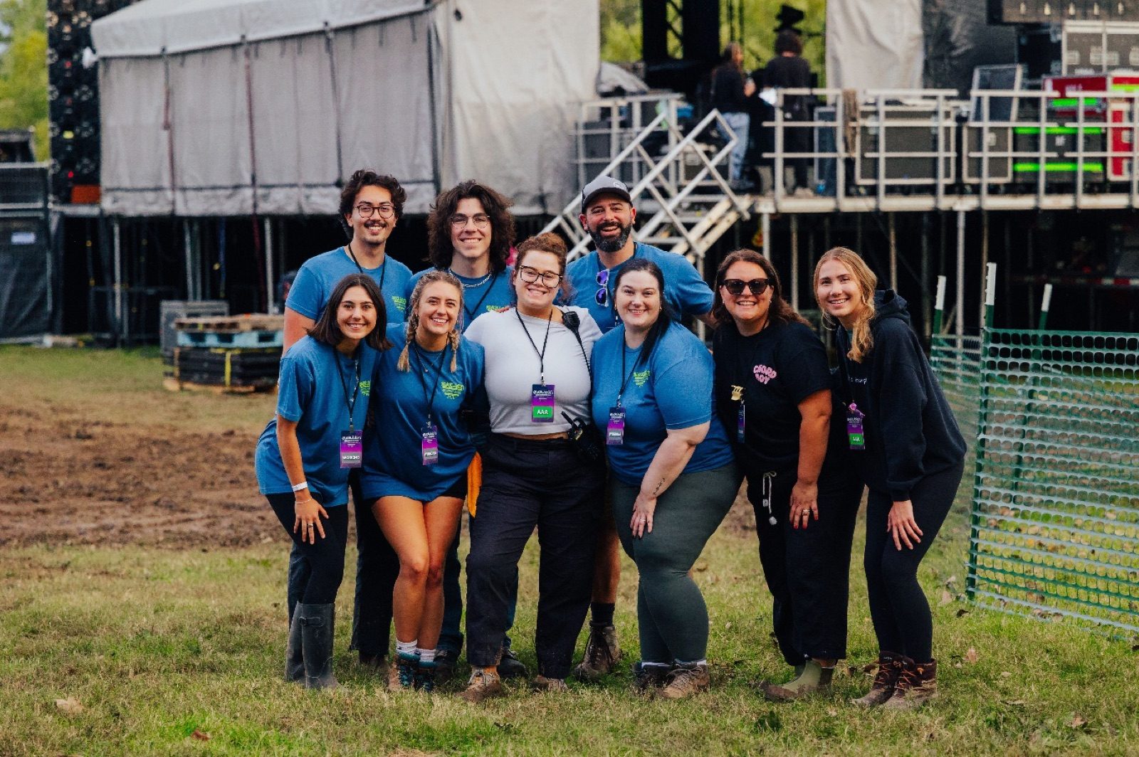 The BEM crew in matching staff shirts and credentials in front of a festival stage at Evolution Fest